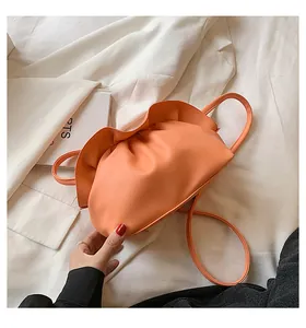 Détail du sac nuage plissé orange vif avec texture en cuir et poignée supérieure