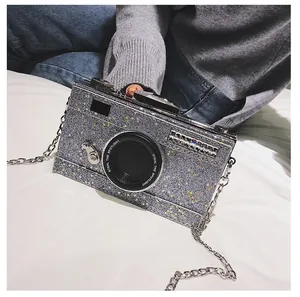 Close-up of a silver sequin camera-shaped crossbody bag with gold star details and metal chain