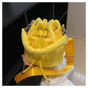 Detail of yellow plush drawstring bucket bag with letter embossing and wide strap
