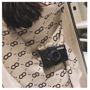 Close-up of a black glitter camera bag with a metal chain and spotlight quote