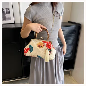 Detail van bamboe handvat en vintage kraanvogelprint op een elegante crossbody tas