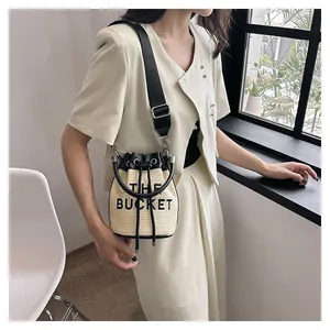 Detailed view of straw bucket bag featuring leather trim and woven adjustable strap