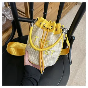Detail of the bucket woven bag with yellow leather trim and wide nylon shoulder strap