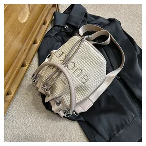 Detailed top view of straw bucket bag with BUCKET embroidery and leather drawstrings