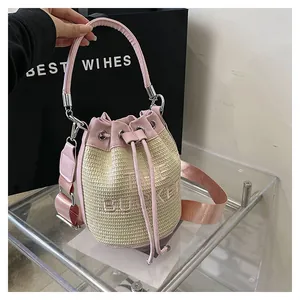 Detail of pink leather trim and straw texture on bucket bag with embroidered lettering
