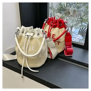 Detail of straw bucket bags with 'THE BUCKET' embroidery and adjustable nylon straps
