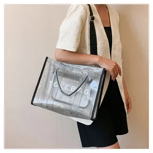 Detail of silver mesh PVC tote bag featuring white TOTE BAG text and black shoulder strap