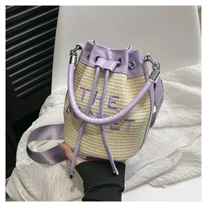 Detail of straw bucket bag with purple leather trim and embroidered lettering