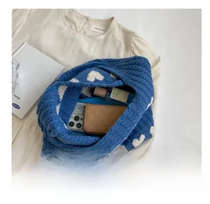Blue knitted heart tote bag showing interior storage capacity with phone and wallet