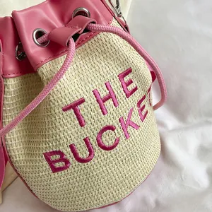 Pink straw bucket bag with embroidered text and drawstring closure for women