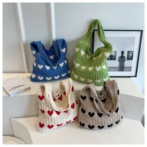 Detail shot of knitted heart tote bags in various colors with textured cable patterns