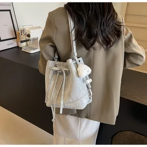 Detail of light gray bucket bag with crinkled texture, drawstring and cloud charm