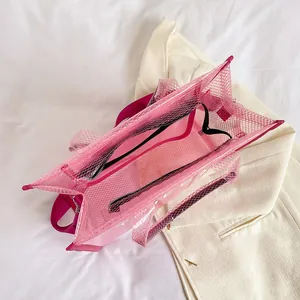 Pink semi-transparent PVC mesh tote bag with white lettering and adjustable shoulder strap