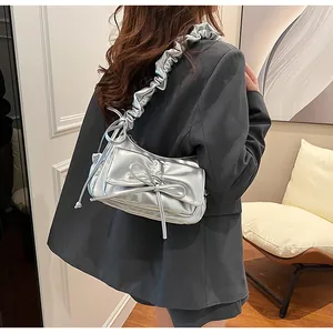 Detail of silver metallic shoulder bag with pleated scrunchie strap and bow detail
