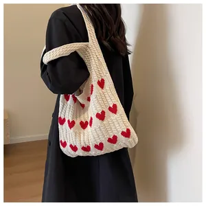 Detailed close-up showing textured knit cable pattern and red hearts on a beige tote bag