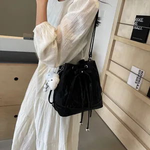 Minimalist black water-ripple bucket bag with cloud plush pendant and drawstring detail