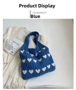 Detail of blue knitted tote bag with white heart patterns on a soft fabric background