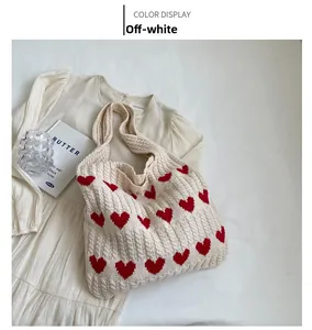 Macro detail of off-white knitted tote bag featuring red woven hearts and soft texture