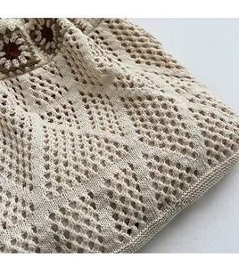 Detailed close-up of beige crochet knit bag with floral sunflower appliques and mesh texture