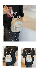 Détail d'un mini sac à dos gris texturé avec double fermeture éclair et design compact