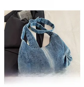 Detail view of denim shoulder bag with pleats, metal rivets and durable double stitching