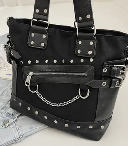 Close-up of black punk tote bag with silver studs and metal chains on canvas material