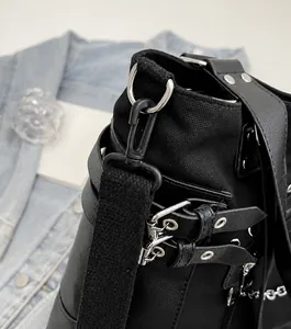Close-up of black canvas and leather tote featuring silver D-rings and metallic buckles