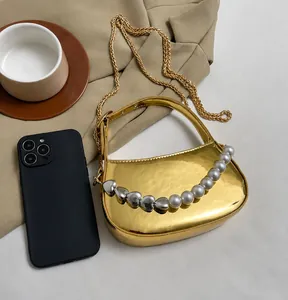 Dettaglio mini borsa dorata a semicerchio con manico in perle e perline a cuore