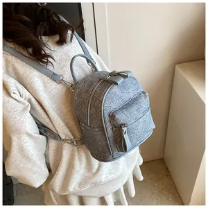 Gros plan d'un mini sac à dos gris clair avec nœud et texture marbrée sur le modèle