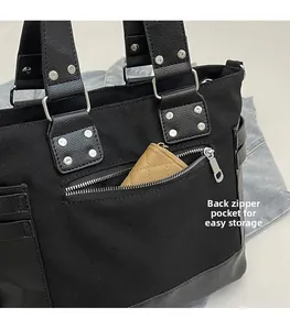 Detail of back zipper pocket on black canvas tote bag with stylish silver rivet accents