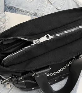Close-up of smooth silver metal zipper and rivet details on the black canvas tote bag