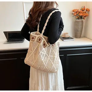 Detail of hand-woven mesh tote bag with floral accents worn by a model in a cafe