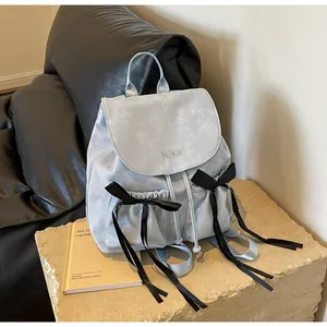 Detail of light blue ballet-style backpack with satin black bow accents and drawstring side pockets