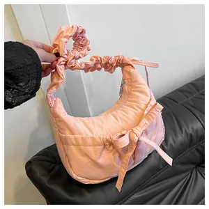 Detail of light pink crescent bag featuring a sweet bow and ruffled scrunchie strap