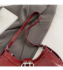 Detailaufnahme der weinroten Lackledertasche mit silberner Metallschnalle und Ösen