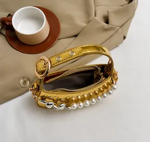 Dettaglio della borsa metallizzata dorata con perle e catena a forma di cuore