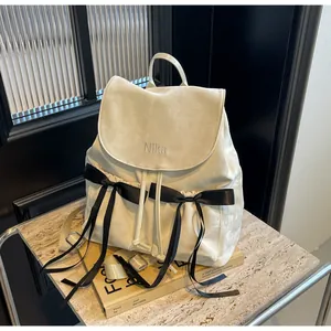 Detail of cream balletcore backpack featuring black lace bows and NiKa embroidery