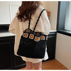 Detail of hand-crocheted black mesh tote bag with orange and white floral granny squares