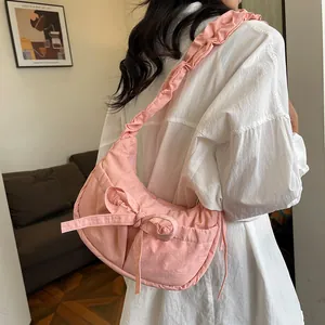 Chic pink crescent shoulder bag featuring pleated straps and bow decoration