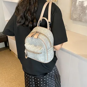 Mini sac à dos texture denim bleu clair avec garniture beige porté en situation réelle