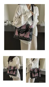 Detail of red stripe canvas tote bag with black leather patchwork and metal rivets
