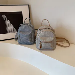 Mini sacs à dos vintage en bleu et beige sur un présentoir blanc au style épuré