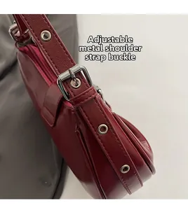 Detail eines verstellbaren weinroten Schultergurts mit silberner Hardware-Schnalle der Tasche