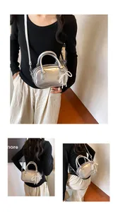 Detail of silver metallic mini bag with round handle and pearl bow charm accessory