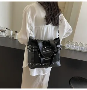 Detail of black punk style tote bag with silver studs and chain on a casual model