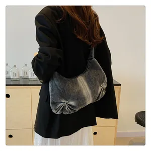 Detail of grey washed denim shoulder bag with pleated texture and silver metal rivets