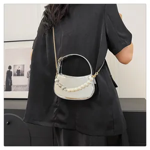 Borsa a mezzaluna argento con manico di perle e catena d'oro indossata da modella