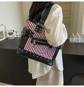 Detail of punk style striped tote bag with leather straps and silver metal studs