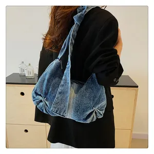 Detail of blue denim hobo bag featuring pleated design and knotted shoulder strap