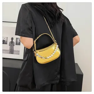 Dettaglio della mini borsa a specchio dorata con perle bianche, cuori e catena in metallo